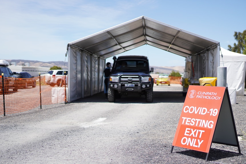 A four-wheel drive under a marquee with a sign saying COVID-19 TESTING EXIT ONLY