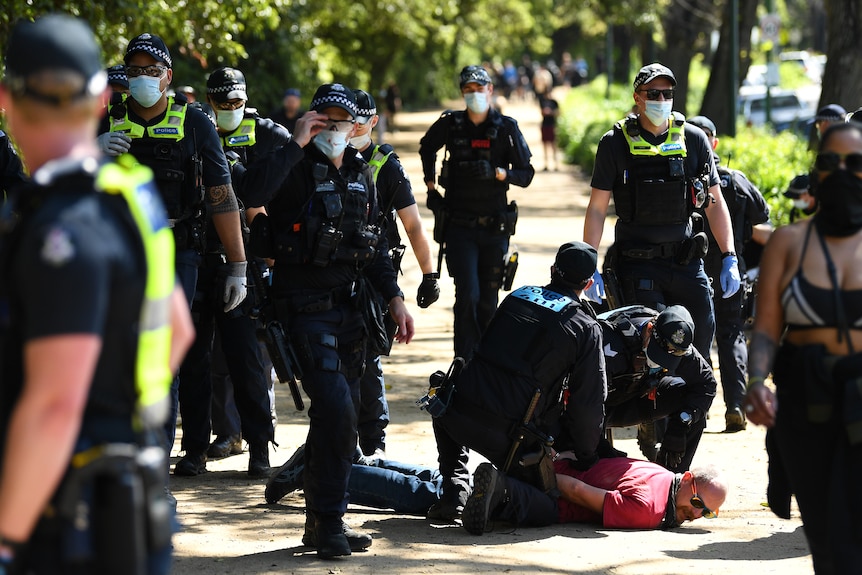 Victoria Police detain a protester near the Royal Botanic Gardens.