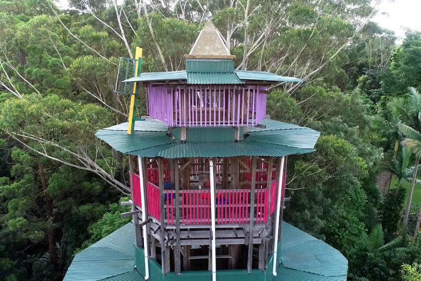 Small circular painted rooms at the top of a tower in line with tree canopies.