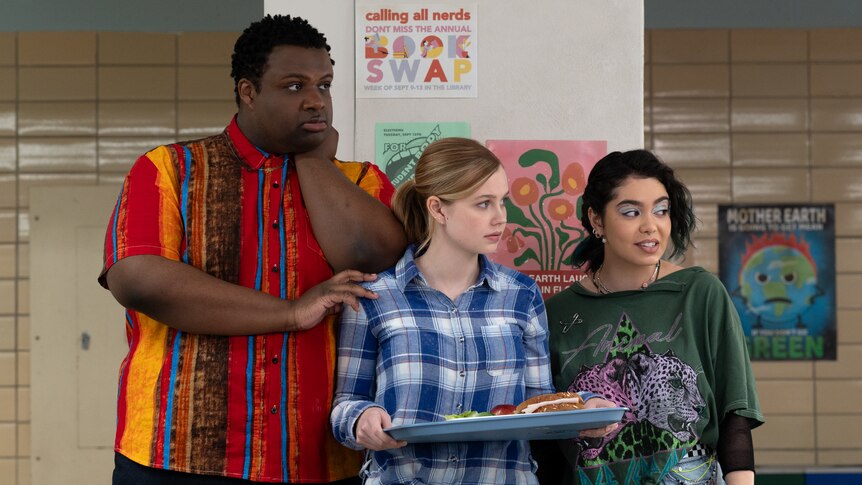 A film still of Jaquel Spivey, Angourie Rice and Auli'i Cravalho standing close together, Rice holding a lunch tray.