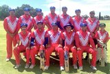 A group of cricketers wearing pink kits and blue caps pose for a photograph.