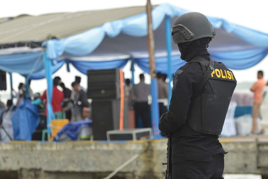 Indonesian policeman guards wharf area.