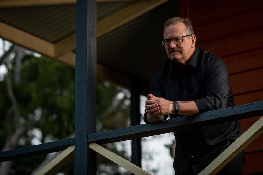 A man leaning against a balcony railing