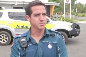 Paramedic standing in front of an ambulance, not smiling