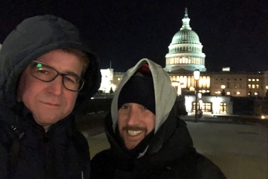 Two men rugged up at night standing outside the US Capitol building