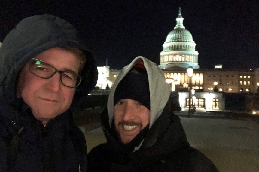 Two men rugged up at night standing outside the US Capitol building