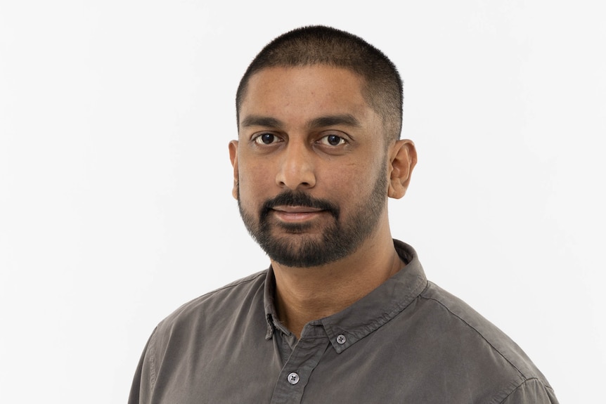 Headshot of Rafi Alam, wearing a brown shirt