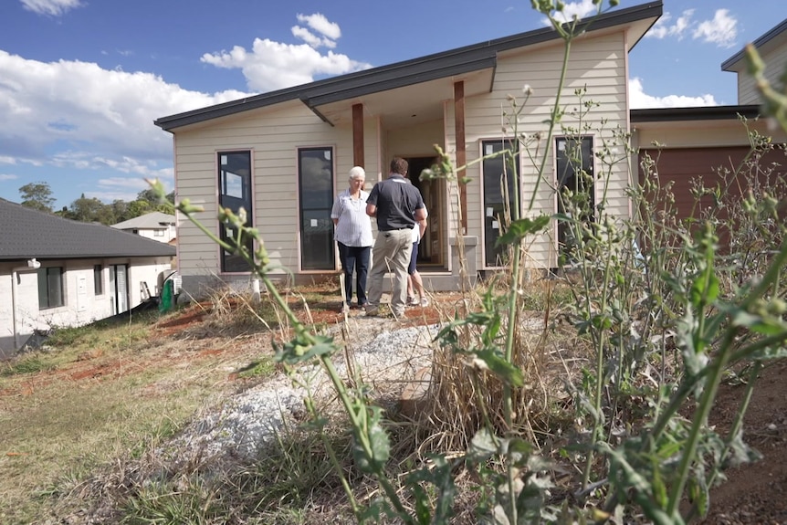 Pauline Duffy and Cobie van Dommele with a building inspector at their northern New South Wales property, weeds in foreground