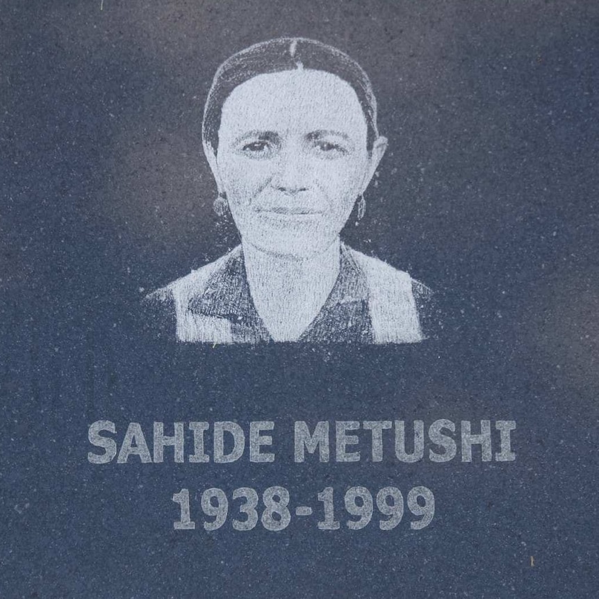 A memorial stone with the face and birth date of a missing woman