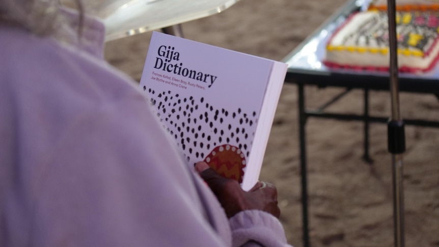 An Indigenous woman holds a Gija dictionary