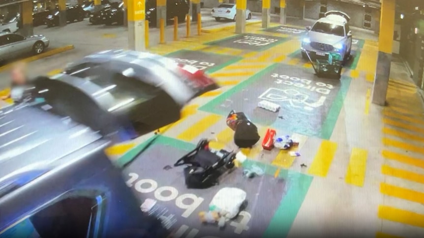 CCTV footage showing the back of a car, with the tailgate up, gorceries and a pram can be seen scattered on the ground