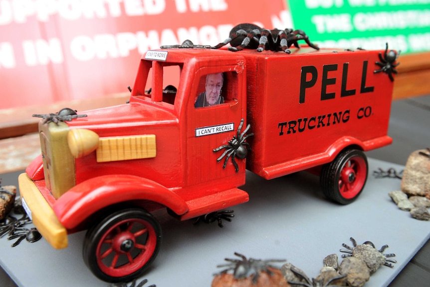 A protest featuring a toy truck with Cardinal George Pell inside and fake spiders all over.