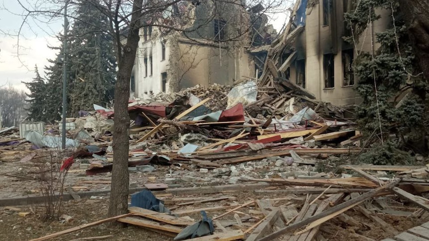 A building is half demolished with two sections still standing. The rest lies on the ground in rubble.