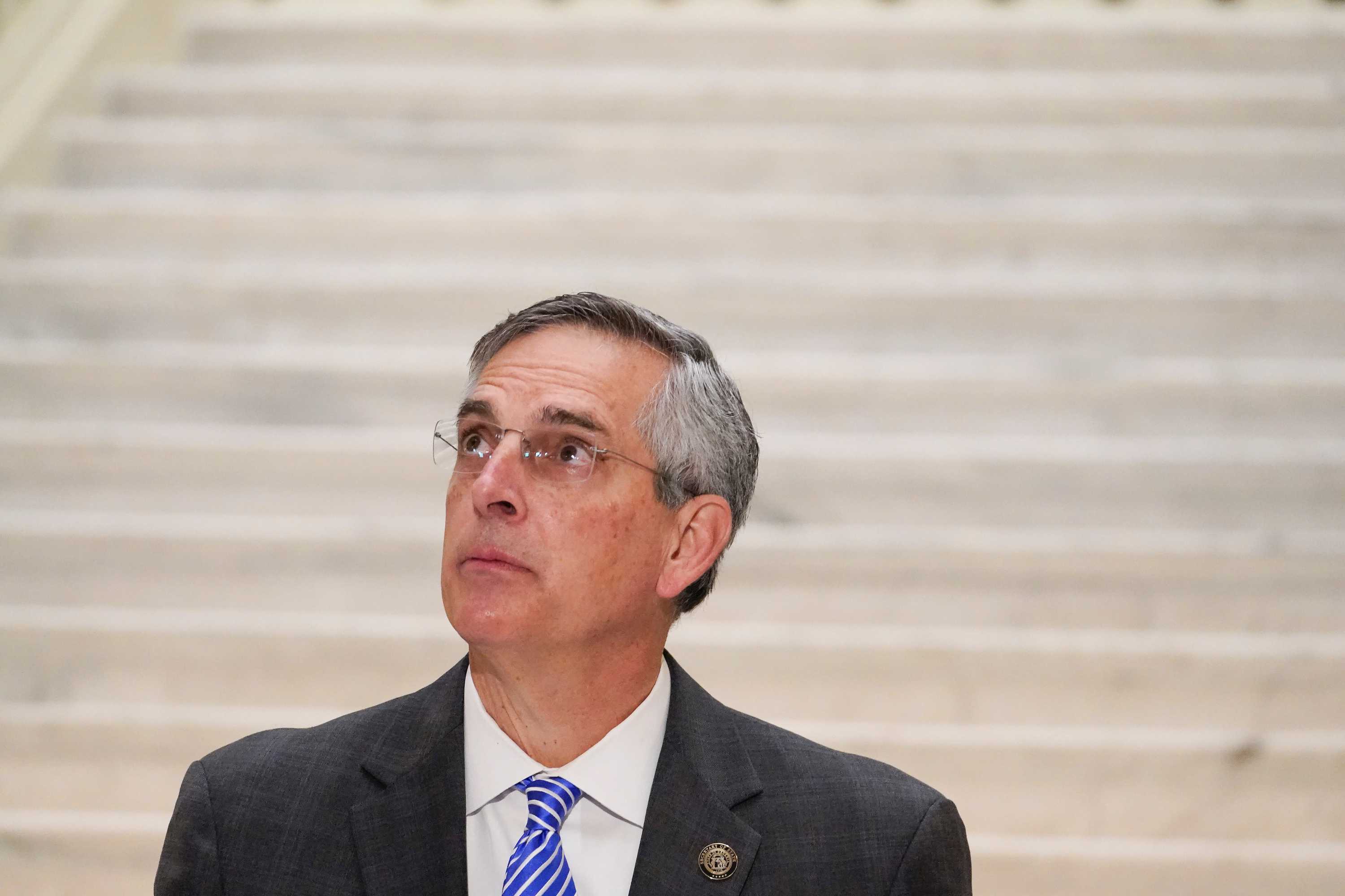 Georgia Secretary of State Brad Raffensperger looks up towards the ceiling as he speaks during a news conference.