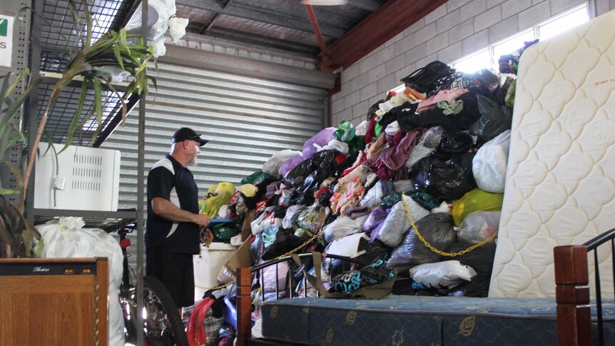 A man standing next to a huge pile of things.