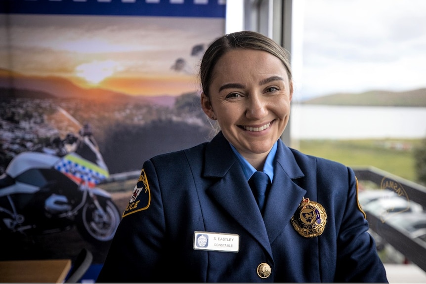 A young woman wearing a blue uniform smiles at the camera