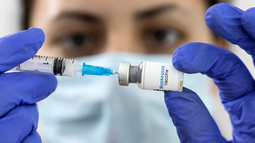 A woman holds a mock-up vial labeled "Monkeypox vaccine" 