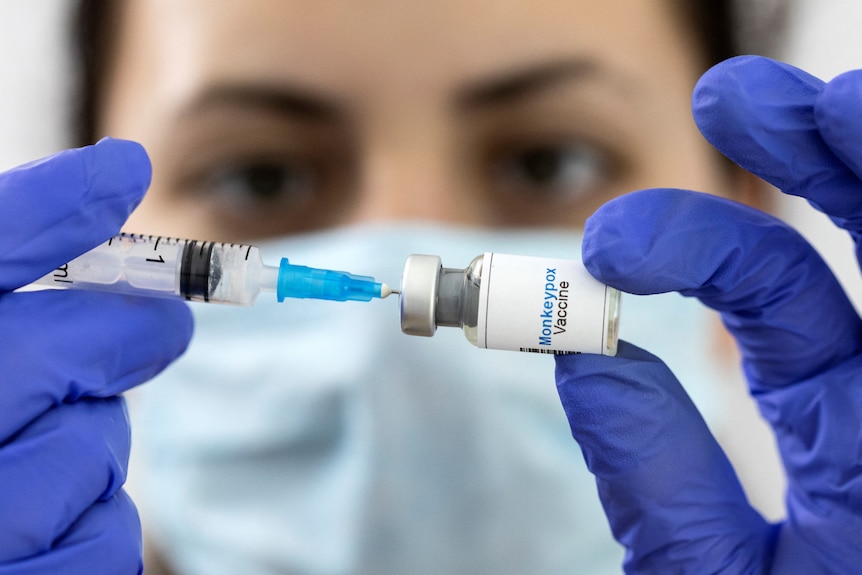 A woman holds a mock-up vial labeled "Monkeypox vaccine" 