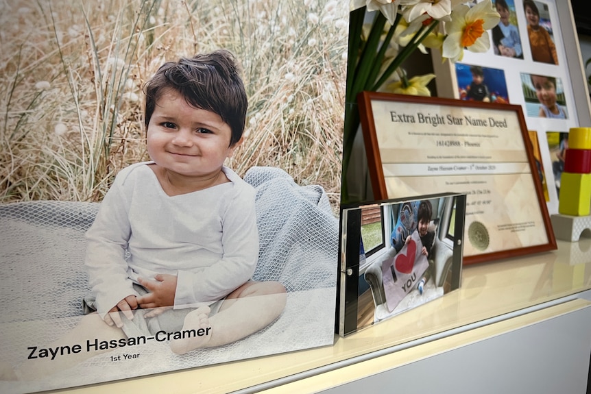 A framed photo of a little boy wearing a jumpsuit.