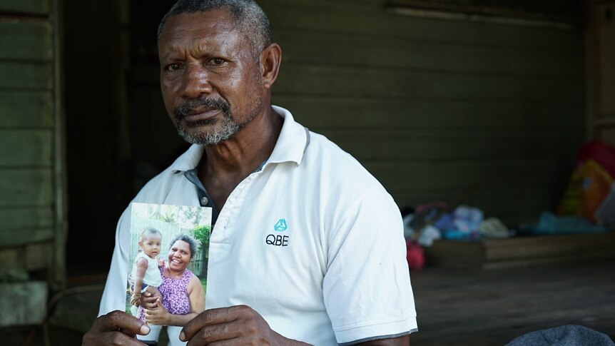Saulo Honorobo holds a picture of his wife Marggeret.
