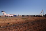 An RFDS plane on an airstrip built on red dirt.