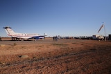 An RFDS plane on an airstrip built on red dirt.