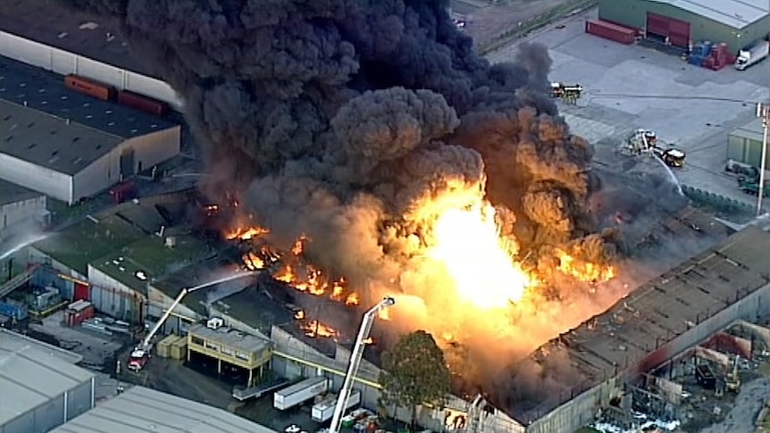 An aerial image shows flames and thick black smoke rising from a West Footscray warehouse.
