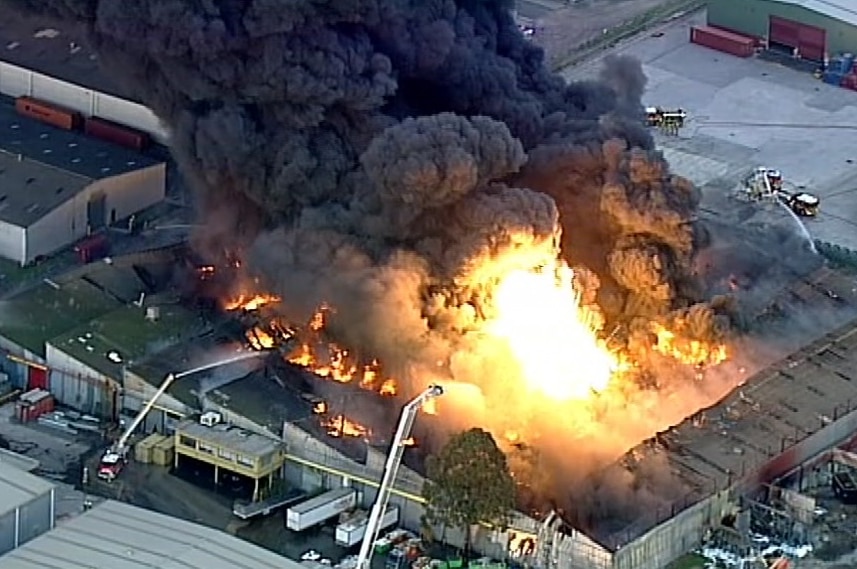 An aerial image shows flames and thick black smoke rising from a West Footscray warehouse.