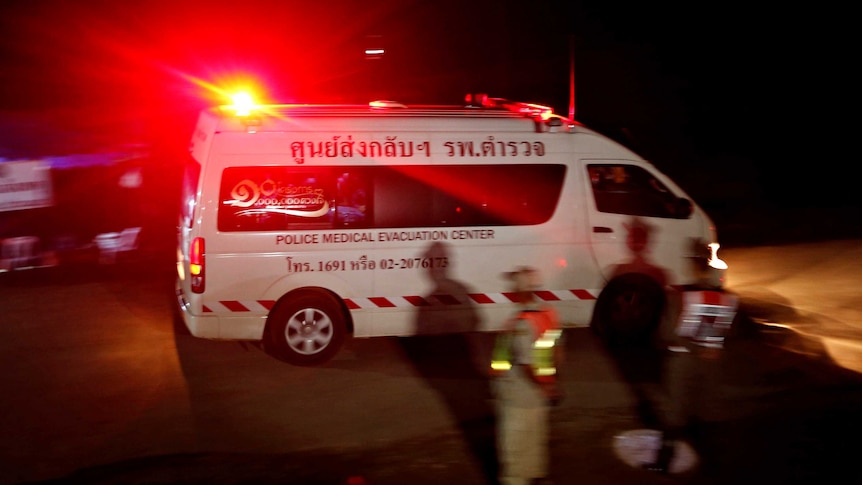 An ambulance with flashing lights leaves the rescue site