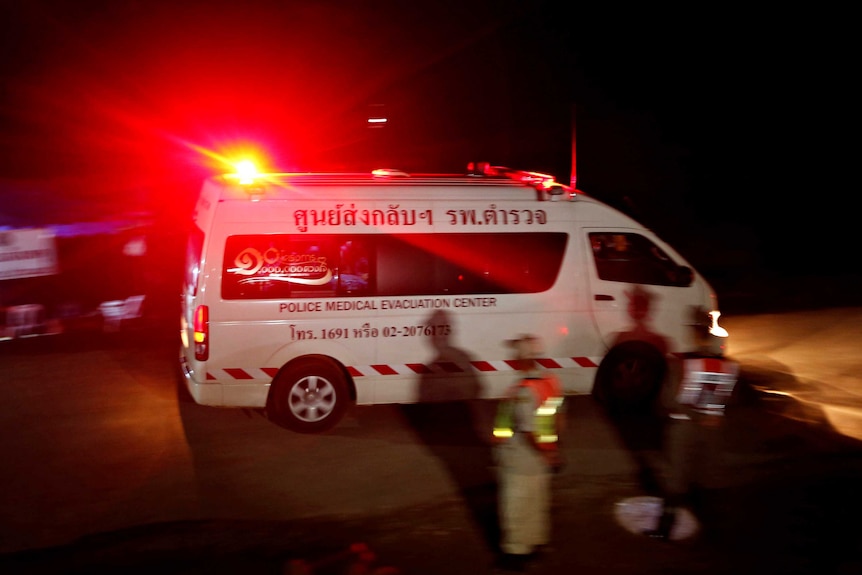 An ambulance with flashing lights leaves the rescue site