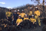 Firefighters standing in burnt landscape.