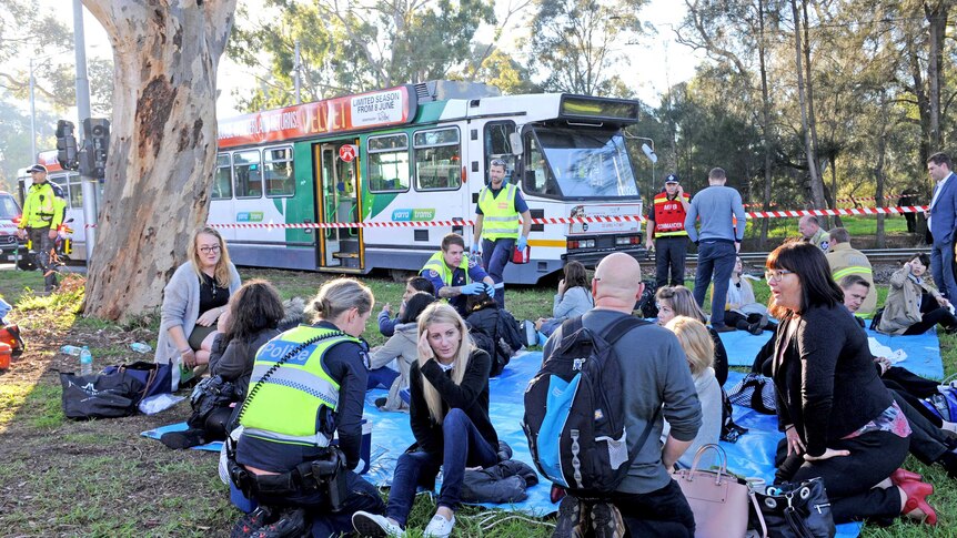 Tram passengers and emergency services at the scene after a truck collides with a tram in Parkville.