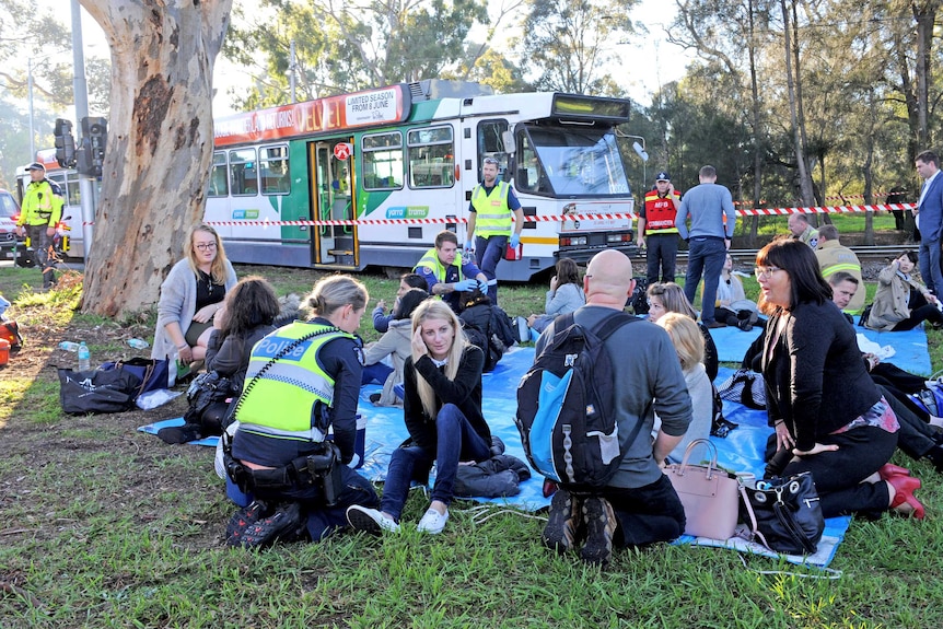 Tram passengers and emergency services at the scene after a truck collides with a tram in Parkville.