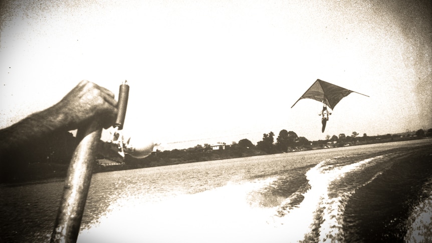 Man flying a hang glider above a river