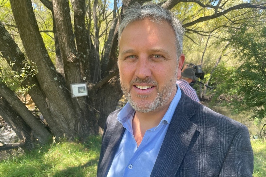 Photo of a man wearing a suit next on a property.