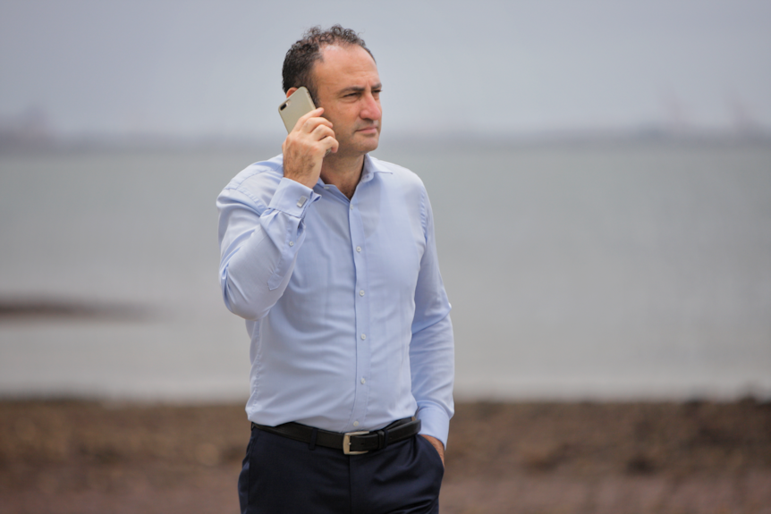 A man stand outside with a mobile phone held to his ear.