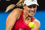 Kerber grips the racket and grits her teeth as she goes to hit the ball.