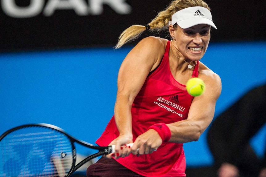 Kerber grips the racket and grits her teeth as she goes to hit the ball.