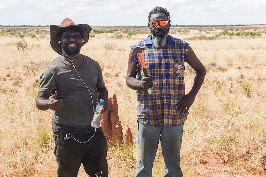 Two men standing out in spinifex in the Great Sandy Desert 
