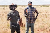 Two men standing out in spinifex in the Great Sandy Desert 