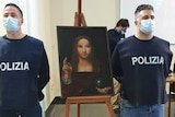 Police officers stand next to a recovered 500-year-old painting titled 'Salvator Mundi'.