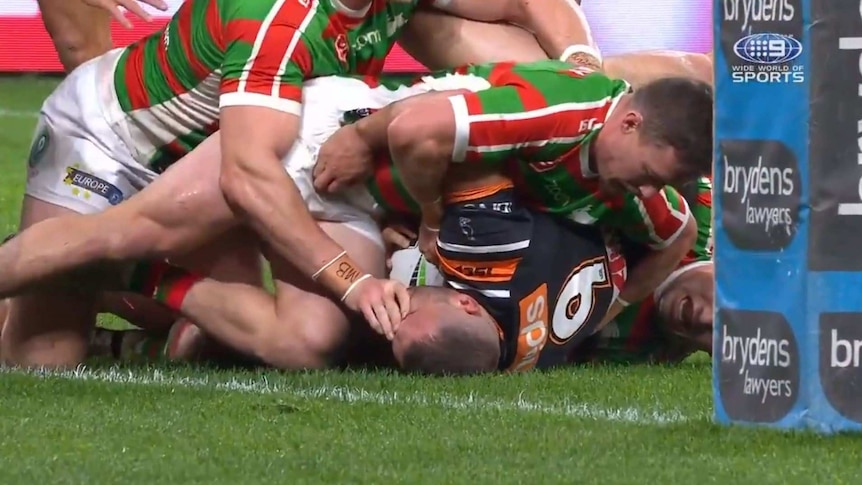 Robbie Farah has the hand of George Burgess near his eye in a tackle featuring many South Sydney Rabbitohs.
