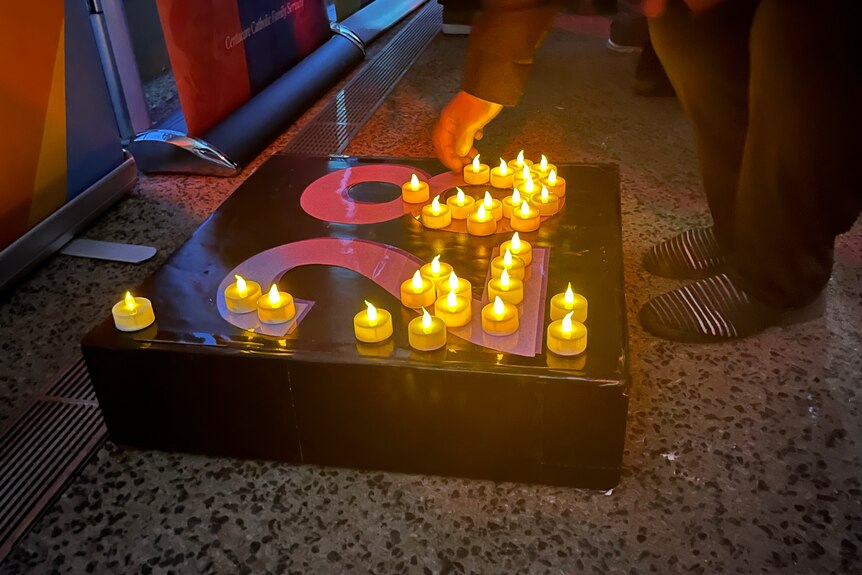 A hand placing an electronic candle on a piece of board with the number 28 on it. 