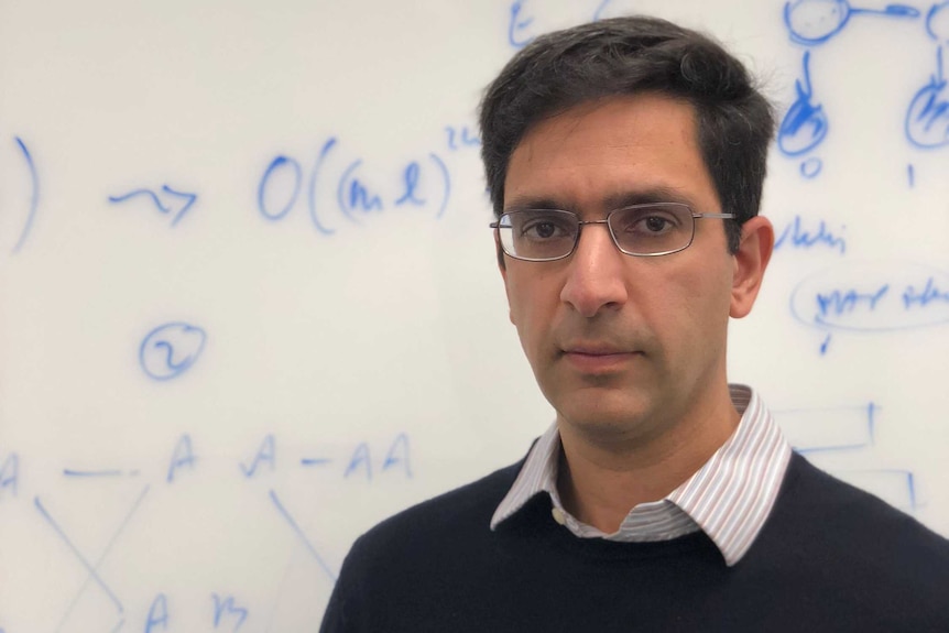 California-based Professor Lior Pachter stands in front of a whiteboard covered in maths equations