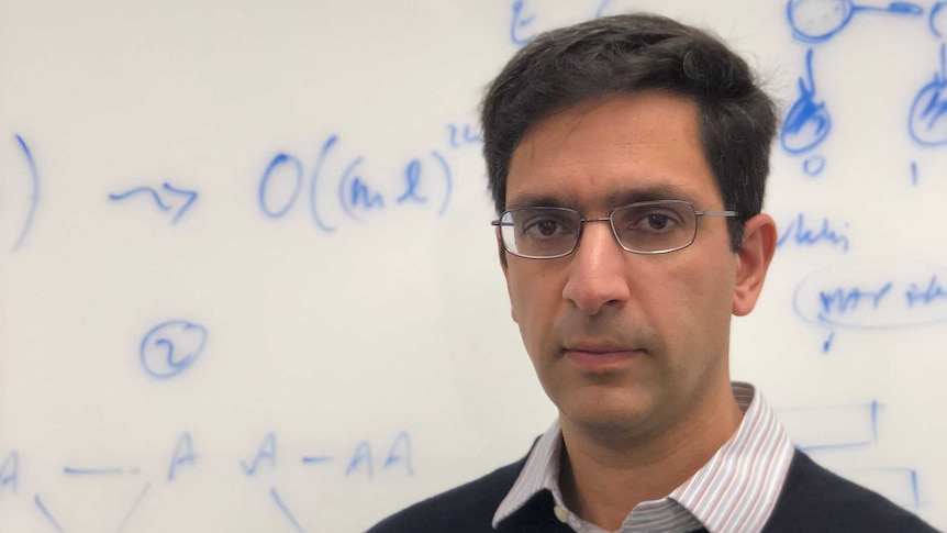 California-based Professor Lior Pachter stands in front of a whiteboard covered in maths equations