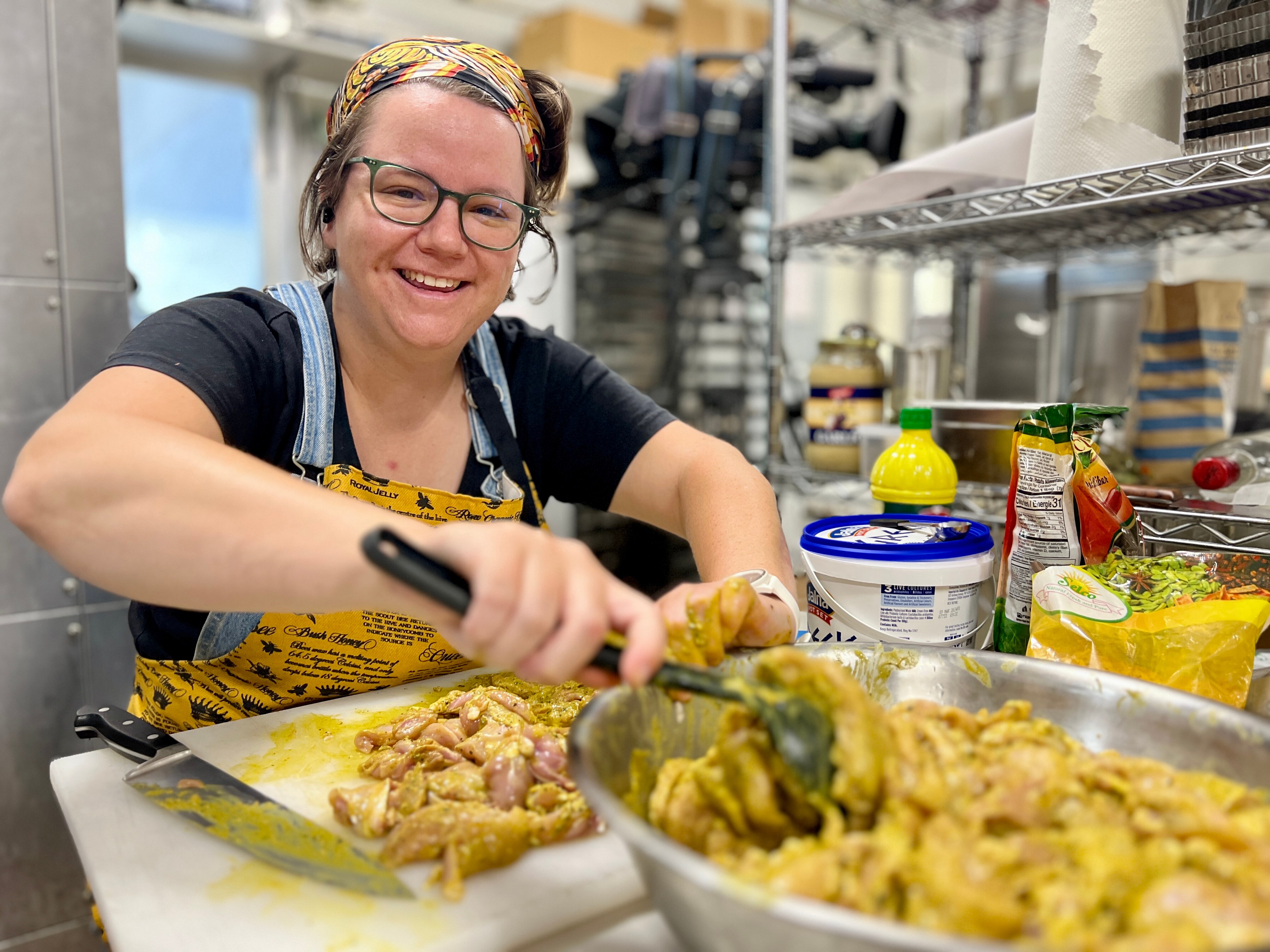 A woman smiling in a kitchen as she cuts food