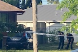 Police tape cordons off a home and car, as officers examine the crime scene.