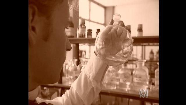 Man holds up beaker in laboratory