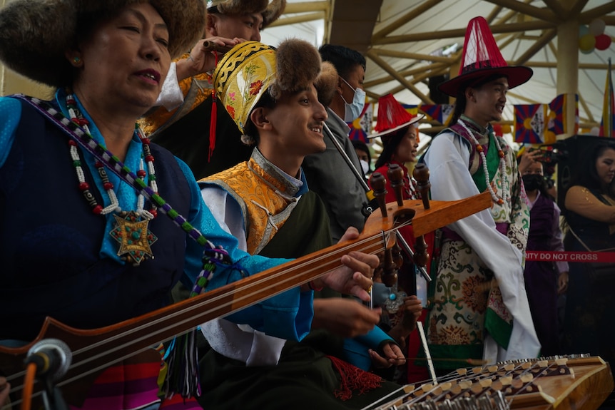 A group of people in traditional Tibetan dress play stringed instruments together