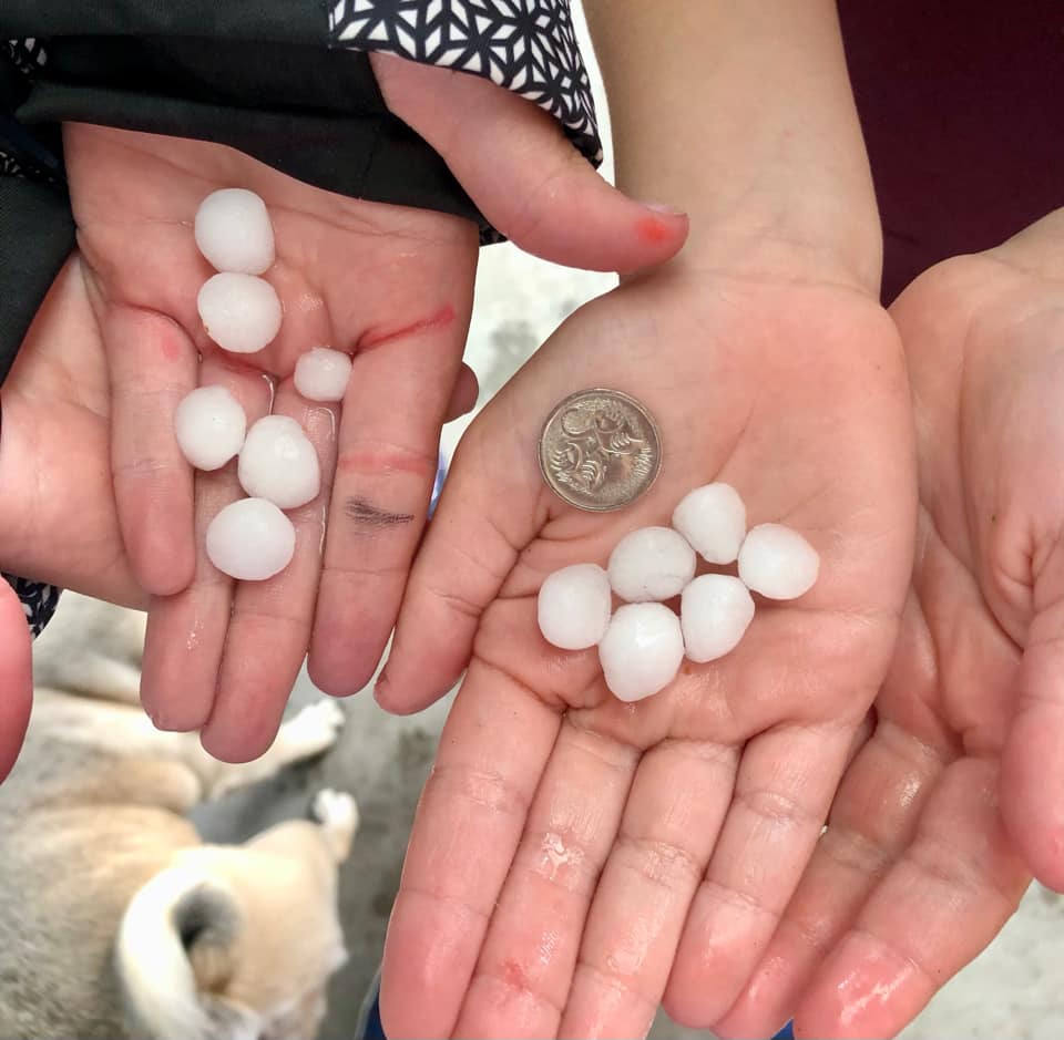 Two people hold hail in their hands.